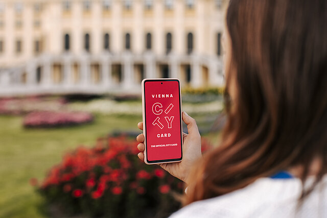 Frau hält Smartphone, das das Vienna City Card Logo zeigt